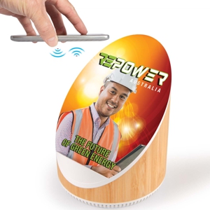 speaker and wireless charger shown with custom printed logo and phone being placed ready for charging